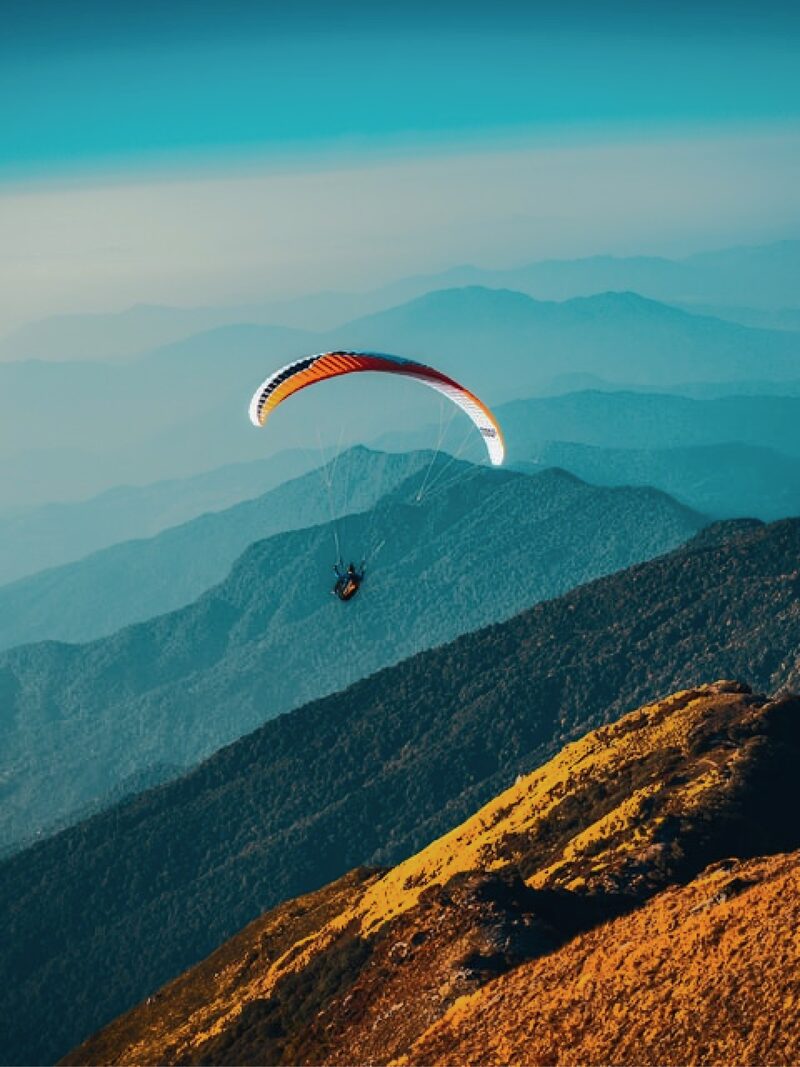 Adventure traveler paragliding over mountain range for luxury outdoor experiences